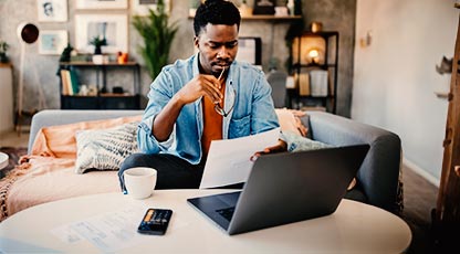 Image of a man using laptop and sitting on a couch at a table