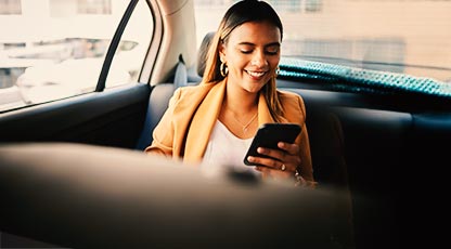 Image of woman sitting in car looking at debit card and phone