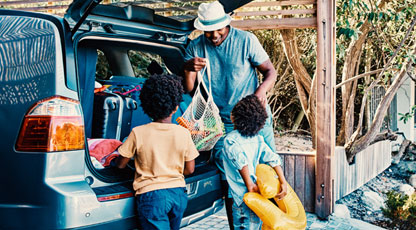 Image of parent and children packing a car