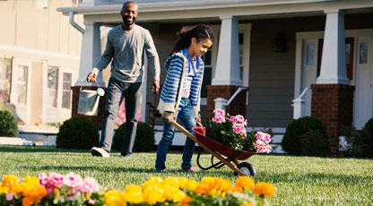Image of a man and young girl gardening in front of a house