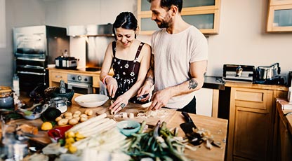 Image of two people in kitchen cooking together and smiling