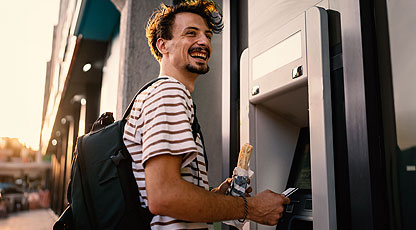A man using an ATM and smiling
