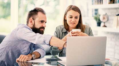 A man and woman looking and pointing something out on a computer screen
