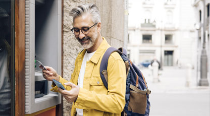 A man using an ATM and smiling