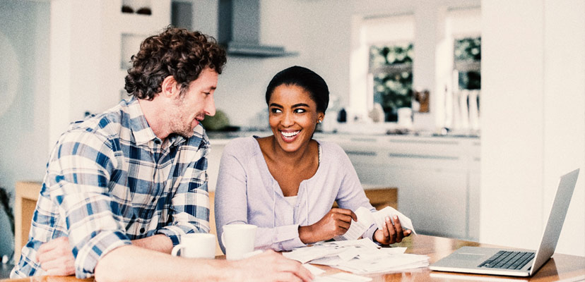 Two people sitting, smiling and looking at a computer