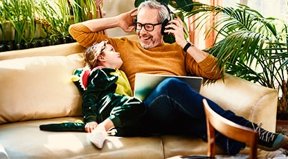 A parent with headphones on smiles at their young child