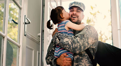 A solider holding his daughter smiling