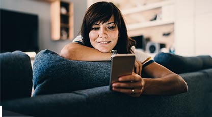 Person laying on a couch looking at their phone with a smile.