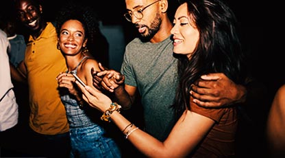 Three young adults in a social setting looking at a smartphone