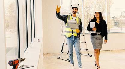 People walking in construction area of  a building with hard hats on