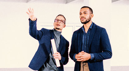 An architect with blueprints in hand explains their vision to a client