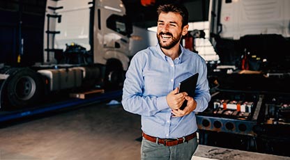 Person smiling and holding a tablet in business setting.