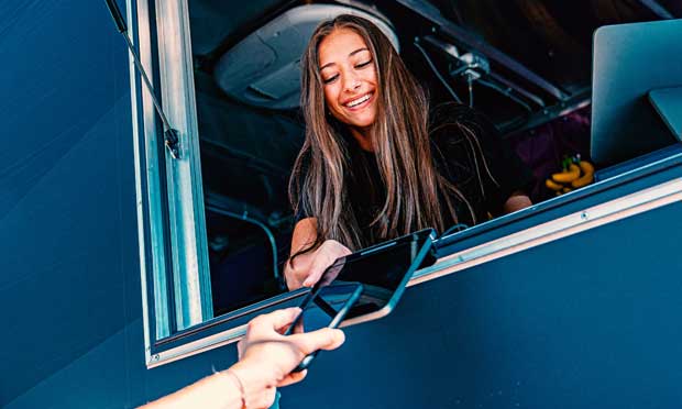 Person tapping their phone at a food truck to make a payment