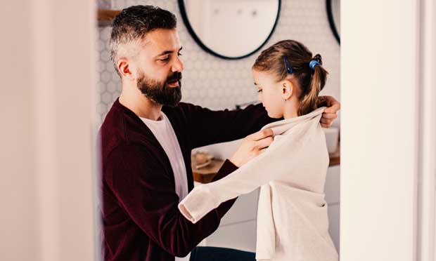 Image of adult helping child put coat on