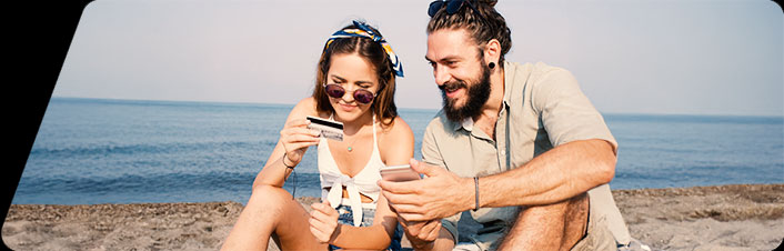 A women and man sitting by the water holding a debit card