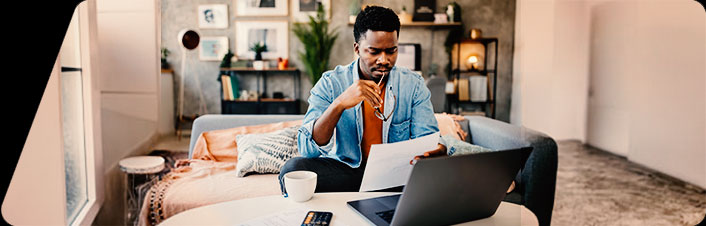 Image of a man using laptop and sitting on a couch at a table