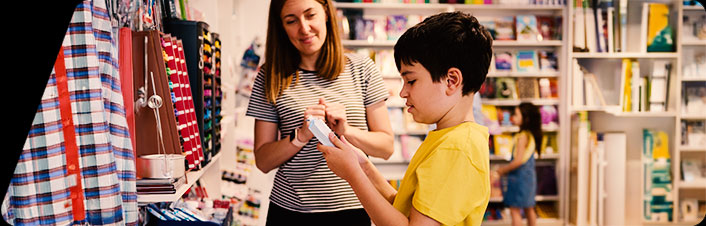 Image of a woman showing a child how to use his money in a store