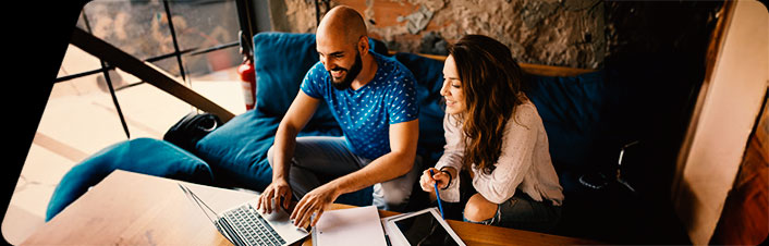 two people sitting down working on a laptop
