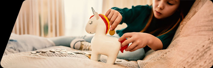Image of child putting coin into unicorn piggy bank