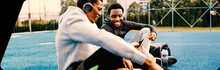 Two younger people sitting and talking, laughing, in a park