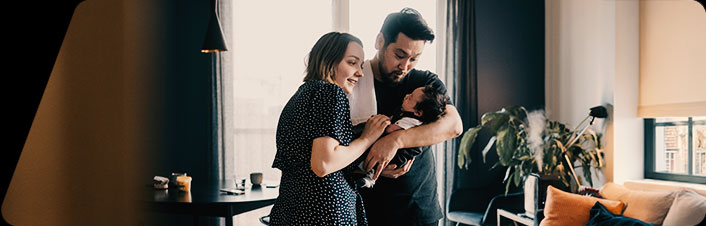 Two people holding a baby and looking at it