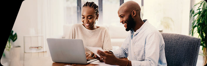 Image of a man and woman sitting in an office looking at a laptop and papers