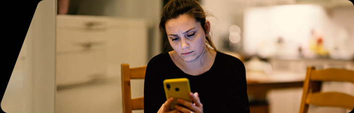 Image of a woman on her phone in the kitchen
