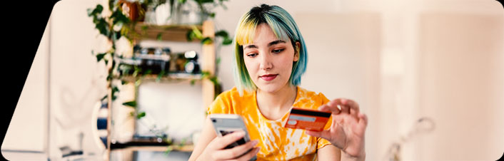 Image of a woman looking at an ATM card and her phone 
